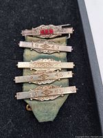 Front view of a green fabric safe driving ribbon with four silver-tone metal bars labeled with years 1923, 1924, 1925, and 1927. The top bar is a labeled '15 Year' in red enamel.
