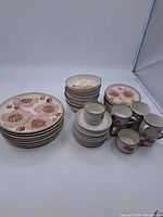 Full set of Denby stoneware dinnerware showing stacked plates, bowls, saucers, and cups.