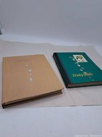 Two stamp albums: one beige with wear and one green labeled 'Stamp Album' with floral design.