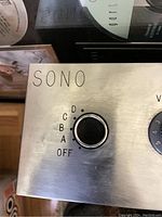 Close-up of the amplifier knob with markings OFF, A, B, C, D and the SONO brand name on the brushed silver metal panel.