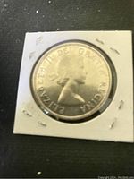 Front view of the 1954 Canadian silver dollar coin in protective holder showing Queen Elizabeth II profile and inscriptions.