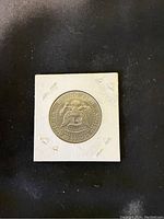 Front side of 1974 USA silver dollar coin showing the eagle and shield emblem in a white cardboard holder with staples.