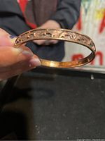 Close-up image of the copper bangle held in hand showing dolphin cut-out details along the band.