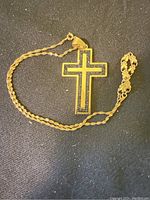 Photo showing the full gold plated chain with cross pendant laid out flat on a dark surface, highlighting the chain style and pendant design.