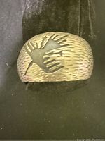 Front view of vintage handmade silver cuff bracelet showing textured surface and two overlapping hand motifs.