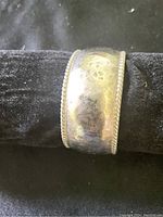 Front view of wide sterling silver cuff bracelet showing hammered finish and twisted rope edge detail