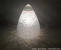 Lamp illuminated on dark background showing speckled swirl pattern casting shadows