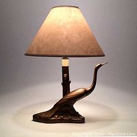 Full view of gilded metal bird lamp with shade lit