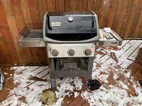 Front view of grill on snowy deck showing lid, control panel and wheels