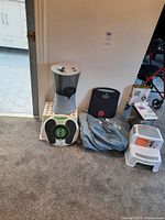 Photo of all lot items grouped together including step stools, humidifier, garbage liners, Bed Basics item, scale, and Revitive Iso Rocker.