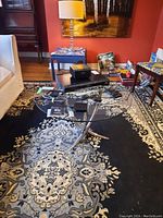 Circular coffee table with metal base and glass top in a living room setting, showing the entire table and surrounding furniture.