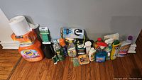 Wide view of cleaning and laundry supplies including Tide Pods detergent, Kirkland dryer sheets, garbage bags, twist ties, and various cleaning chemical bottles.