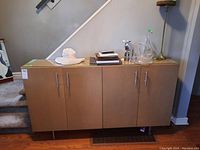 Front view of wood hutch with four doors and various items on top.