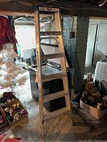 Full view of the 6ft aluminum folding step ladder showing six steps and blue plastic end caps in a basement setting.