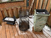 View of two resin planters and black metal serving cart, showing scale and condition with light snow on surfaces.
