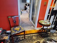 Room view showing wood side chair with upholstered seat and wood side table with stained glass style top.