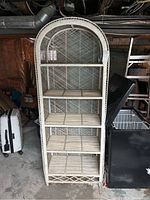 Full front view of tall, arched wicker shelf in basement, showing overall shape and size.