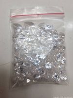 Plastic zip-lock bag containing assorted clear faux diamonds in varying shapes and sizes.