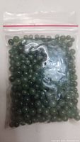 First photo showing a small resealable plastic bag containing numerous round green jade beads.