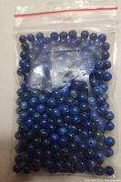 Clear plastic bag containing blue round lapis lazuli beads with drilled holes.