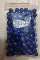 Photo of a resealable plastic bag filled with round deep blue lapis lazuli beads, showing color and drilled holes.