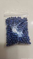 Photo of a clear resealable plastic bag filled with round blue lapis lazuli beads.