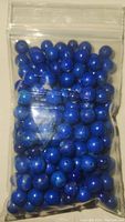 Plastic bag containing multiple round lapis lazuli beads in rich blue color with natural variations.