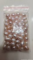 Plastic zip bag containing multiple loose pearls in white and light pink shades.