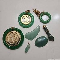 Top-down view of seven jade pieces and pendants laid flat on white surface showing detailed designs