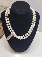 Double strand faux pearl necklace displayed on black stand showing the overall appearance and length.