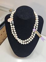 Double strand faux pearl necklace displayed on black necklace stand with visible Kimono tag.