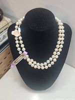 Front view of double strand faux pearl necklace displayed on black necklace bust, showing Kimono fabric tag and heart-shaped metal tag.