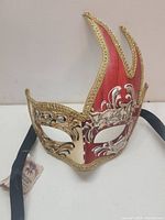 Frontal view of the hand painted mask showing red flame design and gold and silver accents
