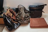 Five purses of various sizes and colors stacked together to show range and style