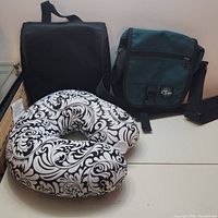 Overview of all three items in the lot: black case, green shoulder bag, and patterned neck pillow