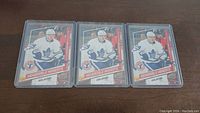 Seven Auston Matthews rookie hockey cards in protective sleeves laid out on a wooden surface.