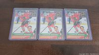 Six Connor Bedard Chicago Blackhawks hockey cards laid out on a dark wooden surface, each in a protective plastic sleeve.