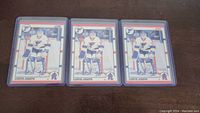 Three Curtis Joseph rookie hockey cards placed side by side on a wooden surface, each in clear plastic protective sleeves.