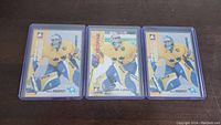 Photo showing three Henrik Lundqvist rookie hockey cards in protective sleeves, all featuring him as a goalie in yellow and blue gear.