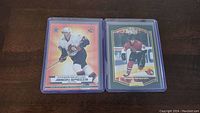 Two Jason Spezza rookie hockey cards in protective sleeves, one with orange-red border and other with black border.
