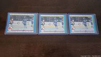 Three Joe Sakic rookie year hockey cards in protective plastic holders displayed side by side on dark surface.