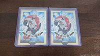 Two Jonathan Huberdeau rookie hockey cards in protective plastic holders displayed side by side on a wooden surface.