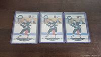 Three Rob Blake rookie hockey cards in protective plastic sleeves, displayed side by side on a wooden surface.