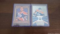 Photo showing two Taylor Hall rookie hockey cards, one with a vintage frame design and the other with a modern action shot, both in protective sleeves.