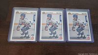 Photo of three identical Teemu Selanne rookie hockey cards in plastic protective sleeves laid out on wooden surface.