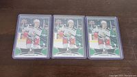 Three Tyler Bertuzzi rookie hockey cards in plastic protective sleeves laid out on a wooden surface.