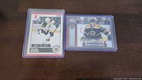 Two Tyler Seguin rookie cards displayed on a wood surface inside protective plastic sleeves.