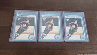 Six Wayne Gretzky rookie reprint hockey cards sleeved, arranged three by three on a dark wood surface.