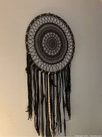 Front view of handcrafted dream catcher with detailed crochet and hanging threads