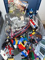 View of tub showing assorted LEGO bricks and mini figures, two LEGO magazines, and blue Mega Man figure inside.